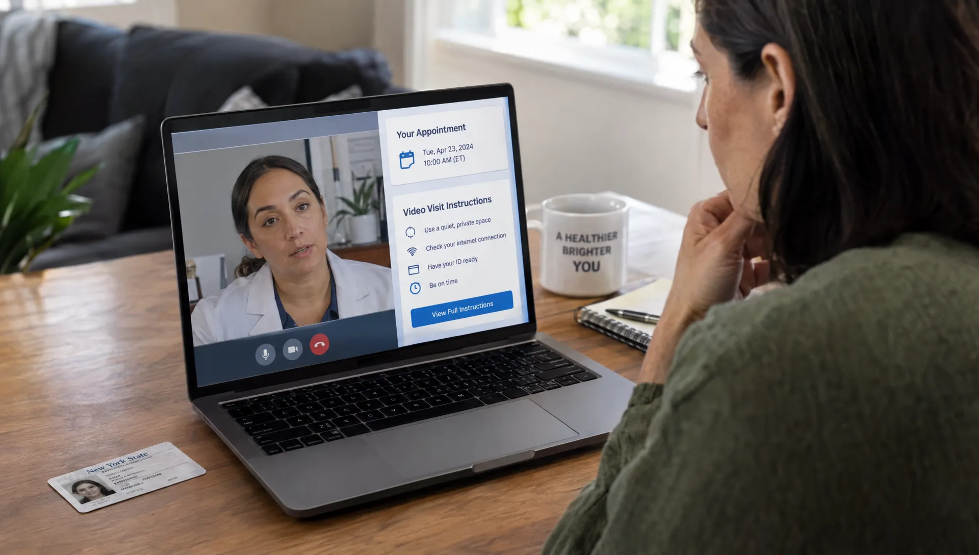 An adult checks appointment details and agency instructions on a laptop during a private video consultation, with an identification card beside the computer.