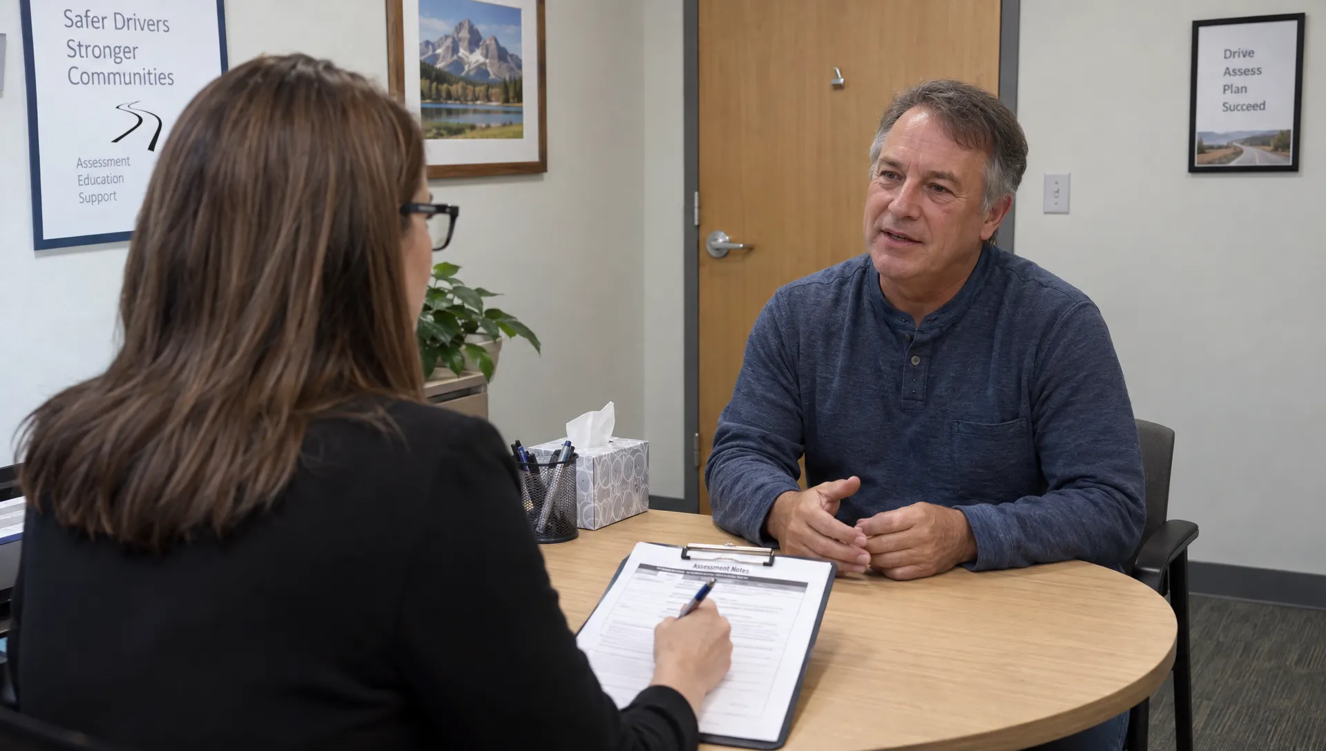 An evaluator interviews a driver and takes notes during a substance use assessment.